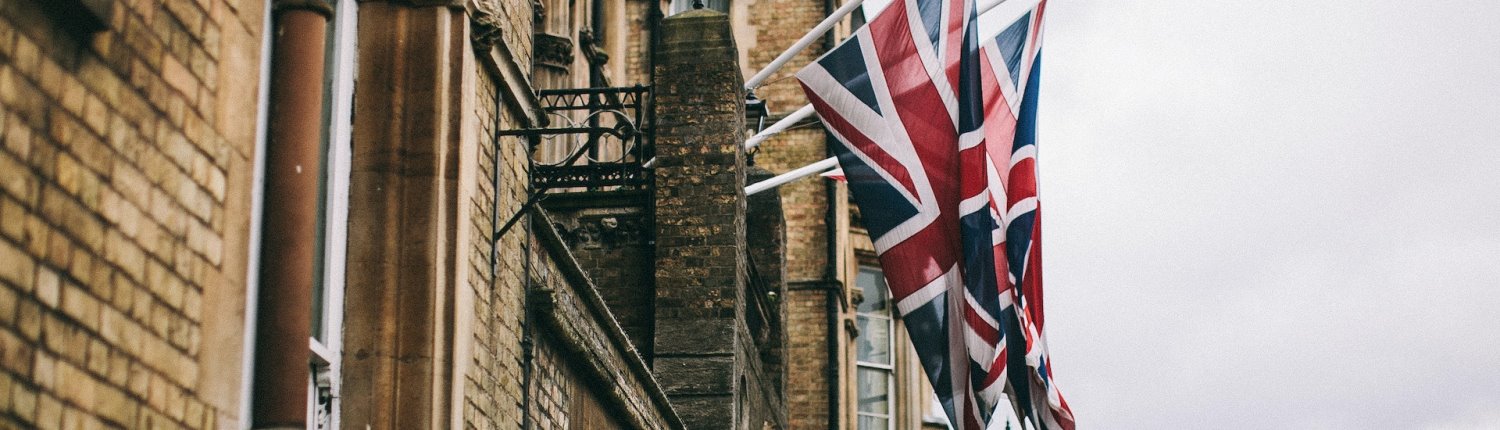 British flags hang from the side of a weathered brick building