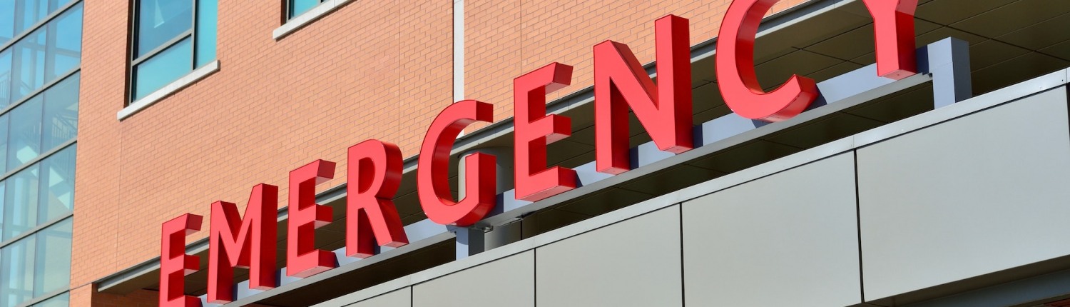 A sign on the side of a building reading 'emergency' in block letters