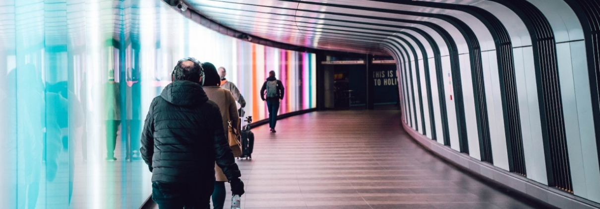 Commuters walk purposefully down a curved tunnel at a train station