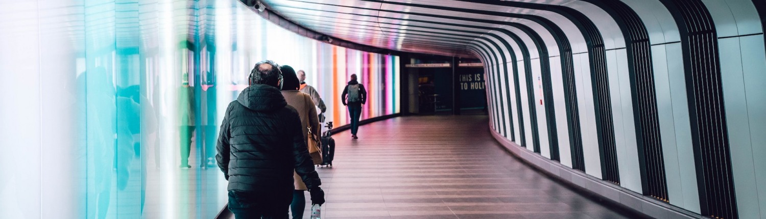 Commuters walk purposefully down a curved tunnel at a train station